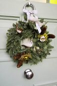 Weihnachtskranz an weisser Haustür mit Tannenzapfen und Tierfiguren