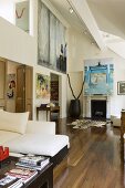 An open-plan living room with walnut parquet and pictures hanging on the wall in front of a fireplace