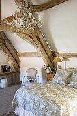 A queen-sized bed and a chandelier in a rustic attic room in a country house