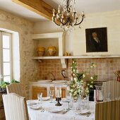 A set dining table and crystal chandelier in a Provencal country kitchen
