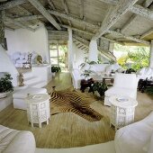 Rustikale Holzdecke im tropischem Einraumhaus mit offenen Ausblicken und Tierfell auf dem Holzboden