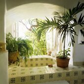 Gefliestes Becken in Fensteröffnung mit Rundbogen und Ausblick in den Garten