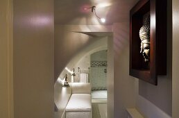 Lichtinszenierung im Bad mit farbigem Licht- und Schattenspiel und ausgestellter Buddhakopf im dunkelroten Rahmen