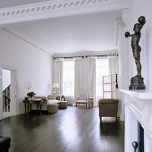 A minimalistic living room with dark wooden floorboards and a black figure on the mantelpiece