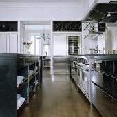 An open-plan kitchen with a stainless steel kitchen counter and black cupboards