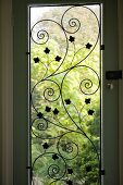 A terrace door with floral metalwork and view into a garden