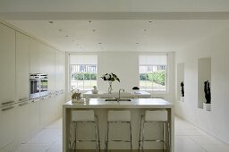 A free-standing kitchen counter with bar stools in the centre of a white kitchen