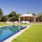 A level pool in a garden with a large gazebo on the terrace