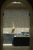 A view through an arched doorway onto a spa pool against a natural stone wall