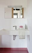 A corner of a bathroom - a designer washstand with a mirror and lights