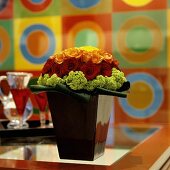 A flower arrangement of different coloured roses in a black, shiny vase