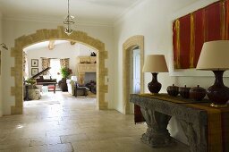 An anteroom with an antique Greek stone table and a rounded archway with a view into a living room