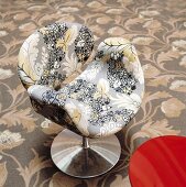 A floral pattern on an upholstered designer chair with a metal foots and a floral carpet