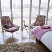 Sessel mit Blumenmuster und Beistelltisch vor Glasfront mit transparentem Vorhang