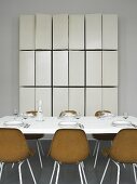 A table laid with brown bucket chairs and a tailor-made wall cupboard with open doors
