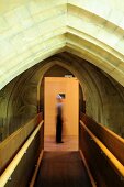 A wooden bridge built into the roof of a church with a person in the doorway