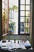 A desk in front of an open window with a view of a courtyard