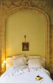 A bed against a bricked up archway set with breakfast coffee in an elegant apartment