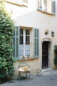 A facade of a country house with bars at the windows and a straw hat on a chair