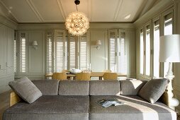 Sofa with white table lamp and in a living room with bright gray paneling