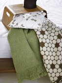 Wooden tray on a bed with pillows and patterned bedspread
