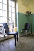 Black plastic chair in designer style in front of a balcony door and painted corner of a room