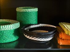 Green basket set next to black and white patterned wicker bowls on a black surface