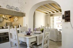 Open plan design dining room (country home style) with carved chairs and a view through the rounded doorway to the timber beam ceiling in the living room