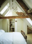 Beamed attic bedroom with a cat sitting on a beam.