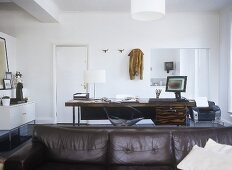 Home office with desk and computer behind leather sofa