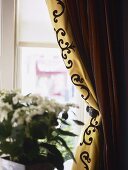 A detail of a window with gold curtains held back