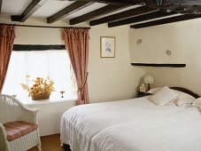 Pair of single beds in country style bedroom with beamed ceiling