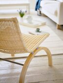 Sitting room with wicker chair on white painted floorboards.