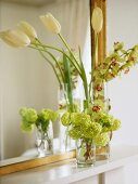 A detail of a flower arrangement on a mantelpiece, showing hydrangea flowers and tulips, against a mirror