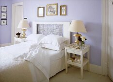 A traditional, pale blue bedroom with double bed, decorative headboard, side tables, lamps