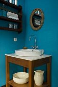 Corner of a room painted blue with a wash stand and washbasin