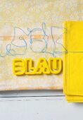 Yellow plastic letter on a piece of patterned fabric
