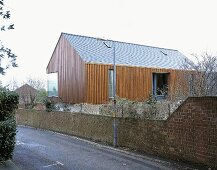Vertical wood panelling on a newly built house with a corner window and a brick wall