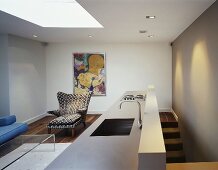 An open-plan living room with a designer kitchen counter and a retro-look armchair