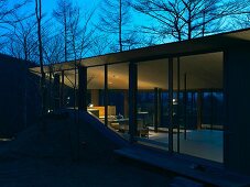 A newly built house with a floor-to-ceiling glass facade in the evening