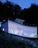 Neubauhaus mit geschwungener Fassade am Hang in Abendstimmung, Haus Izu von Atelier Bow-Wow, Tokio, Japan