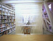 An office with a transparent room divider and a built-in bookshelf