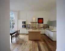 An open-plan designer kitchen with a kitchen counter and an antique dining table