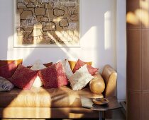 A light brown leather sofa with cushions against a white wall