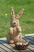A straw rabbit figure with a nest on wooden boards