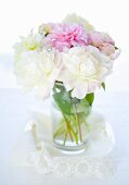 Peonies in a vase on a lace cloth