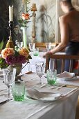 A table laid with green glasses, flowers and candles