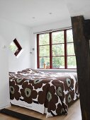 Doppelbett mit braun gemusterter Tagesdecke in einem Schlafzimmer