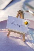 A place card with the name 'Anne' on a mini easel with a daisy