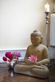Buddhastatue und Blumenvase im Yoga-Übungsraum
